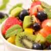 3 przepisy na sałatkę owocową – smakowity posiłek w czasie upałów - zdjęcie ilustracyjne wpisu na bloga. Zdjęcie przedstawia miskę z pokrojonymi owocami: kiwi, truskawka, winogrona