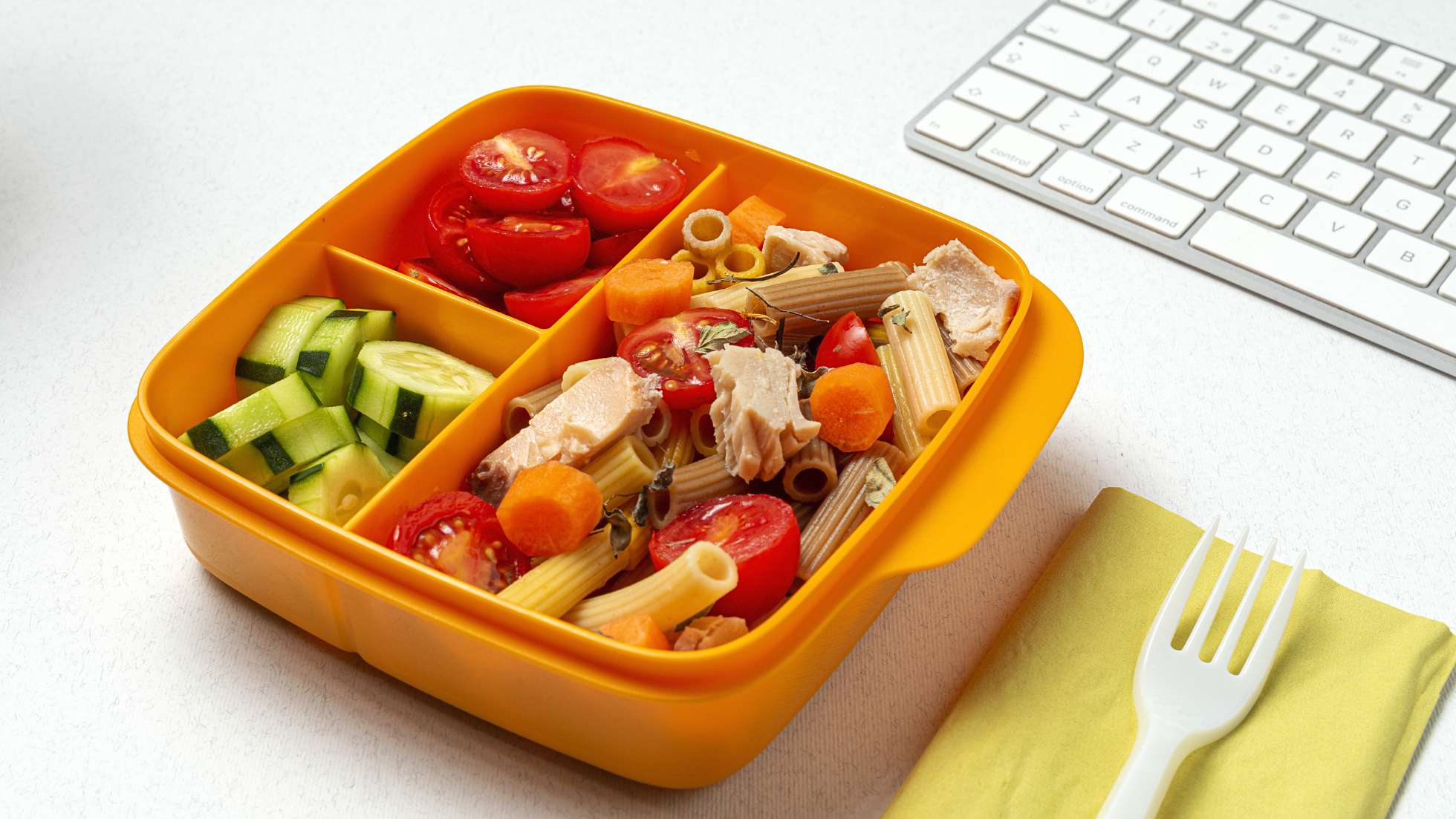 Znaczenie drugiego śniadania w diecie dziecka i dorosłego - zdjęcie ilustrtacyjne wpisu na bloga przedstawiające lunchbox na biurku przed klawiaturą